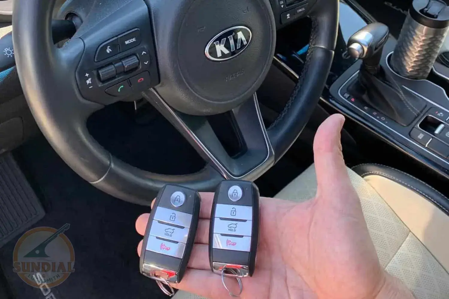 Hand holding Kia car keys inside vehicle.