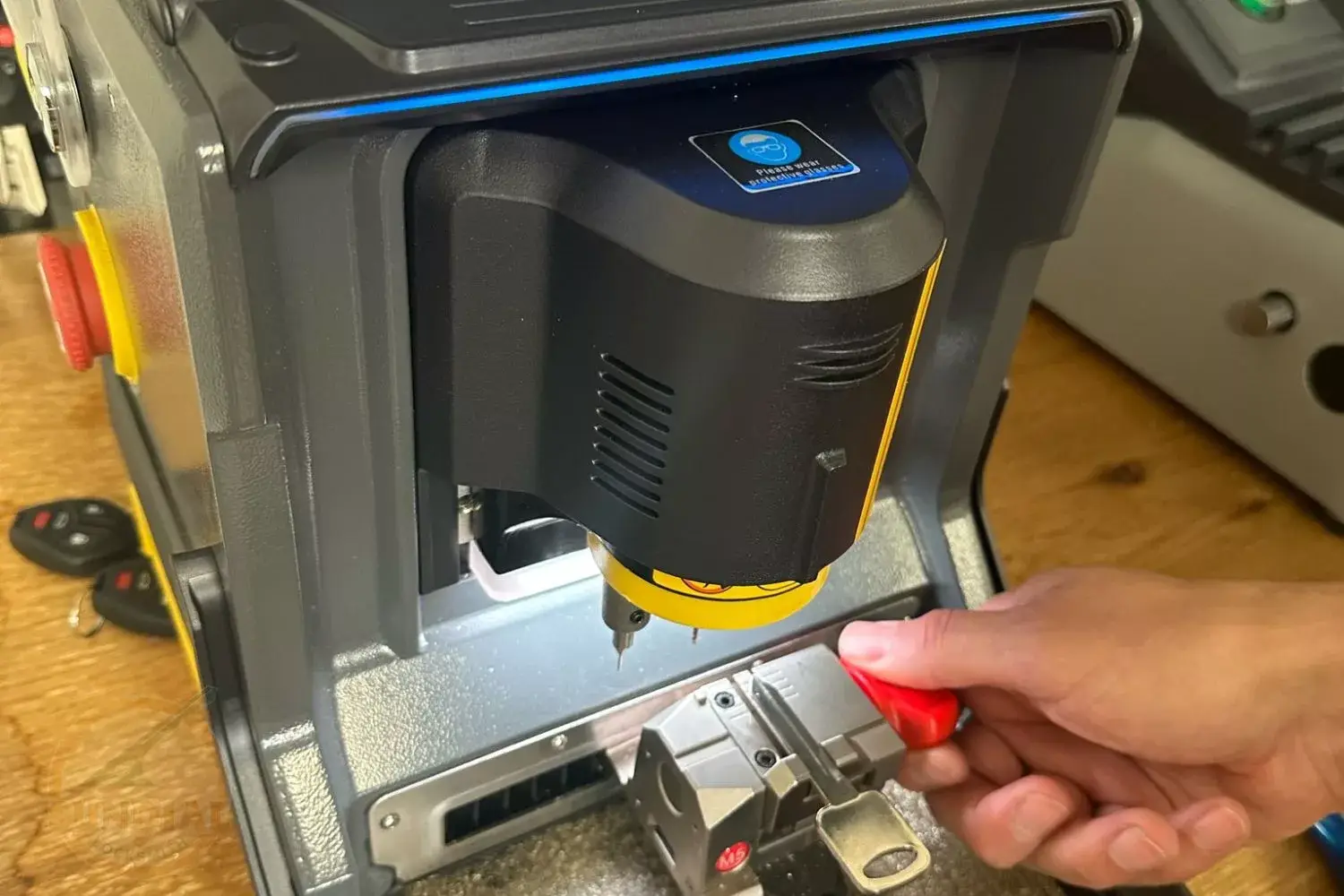 A person's hand operating a key cutting machine, duplicating a key