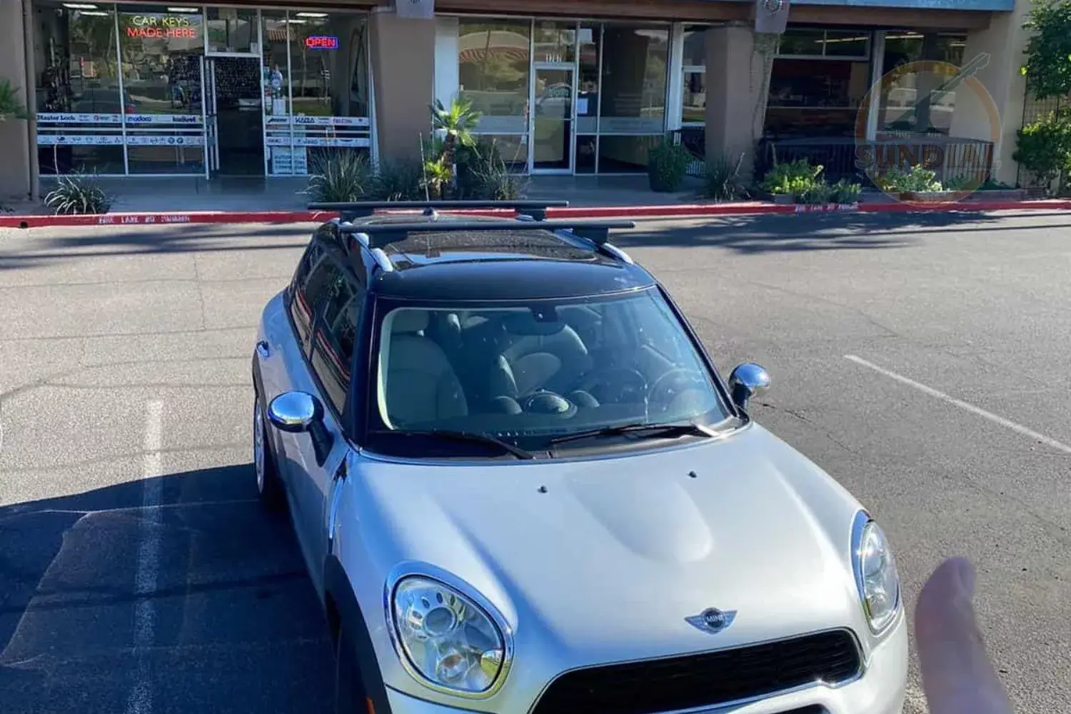 Car parked outside storefront on sunny day.