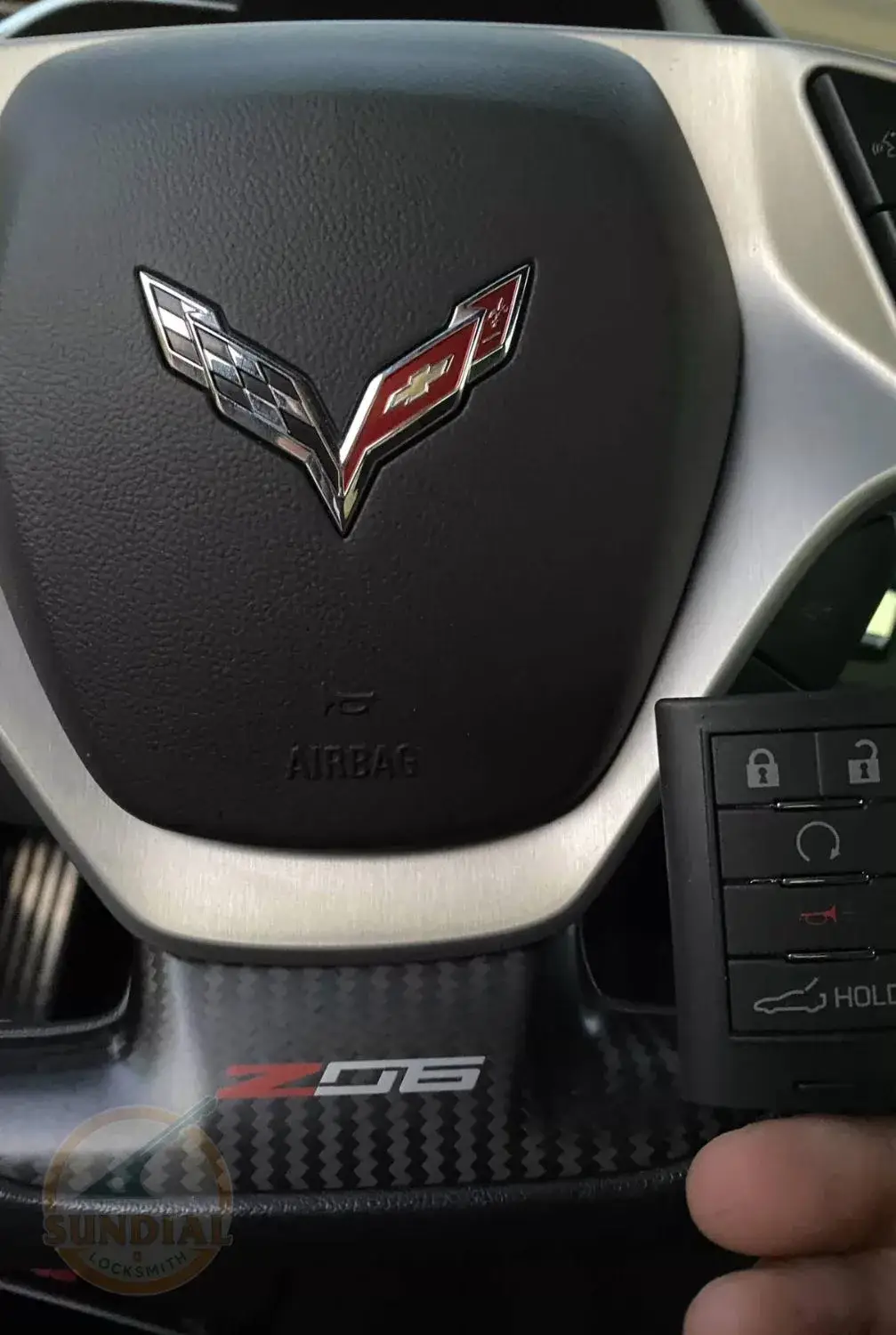 Close-up of a vehicle's steering wheel emblem and key fob in hand