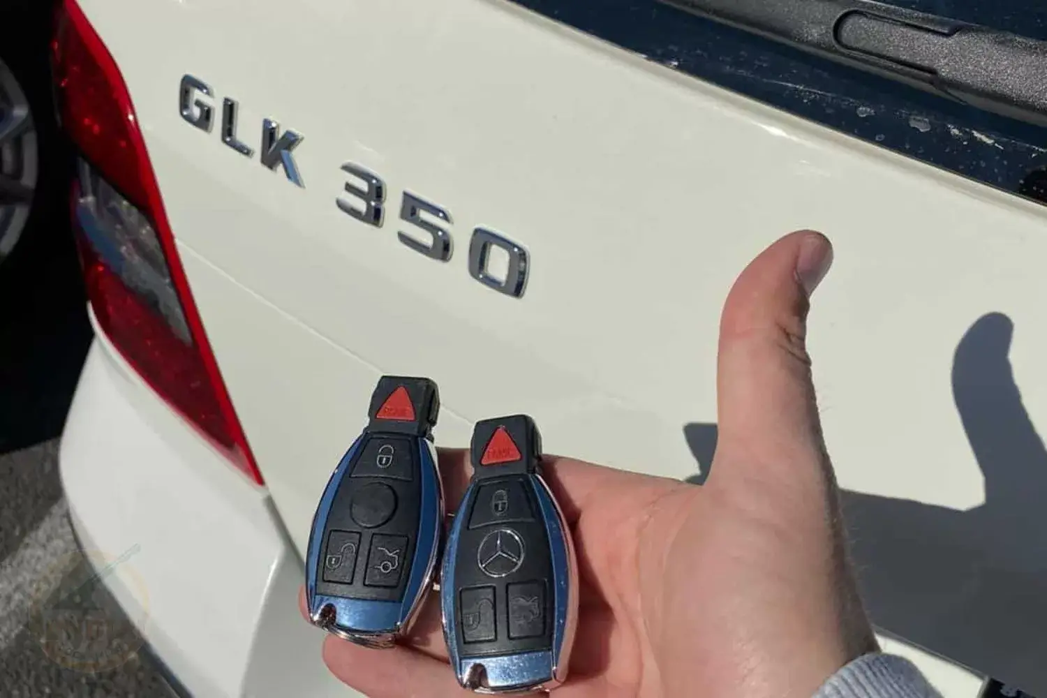 Hand holding Mercedes-Benz keys near GLK 350 vehicle.
