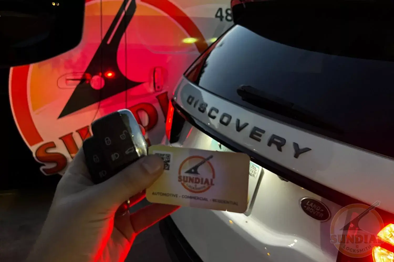 Hand holding keys near vehicle with locksmith branding.