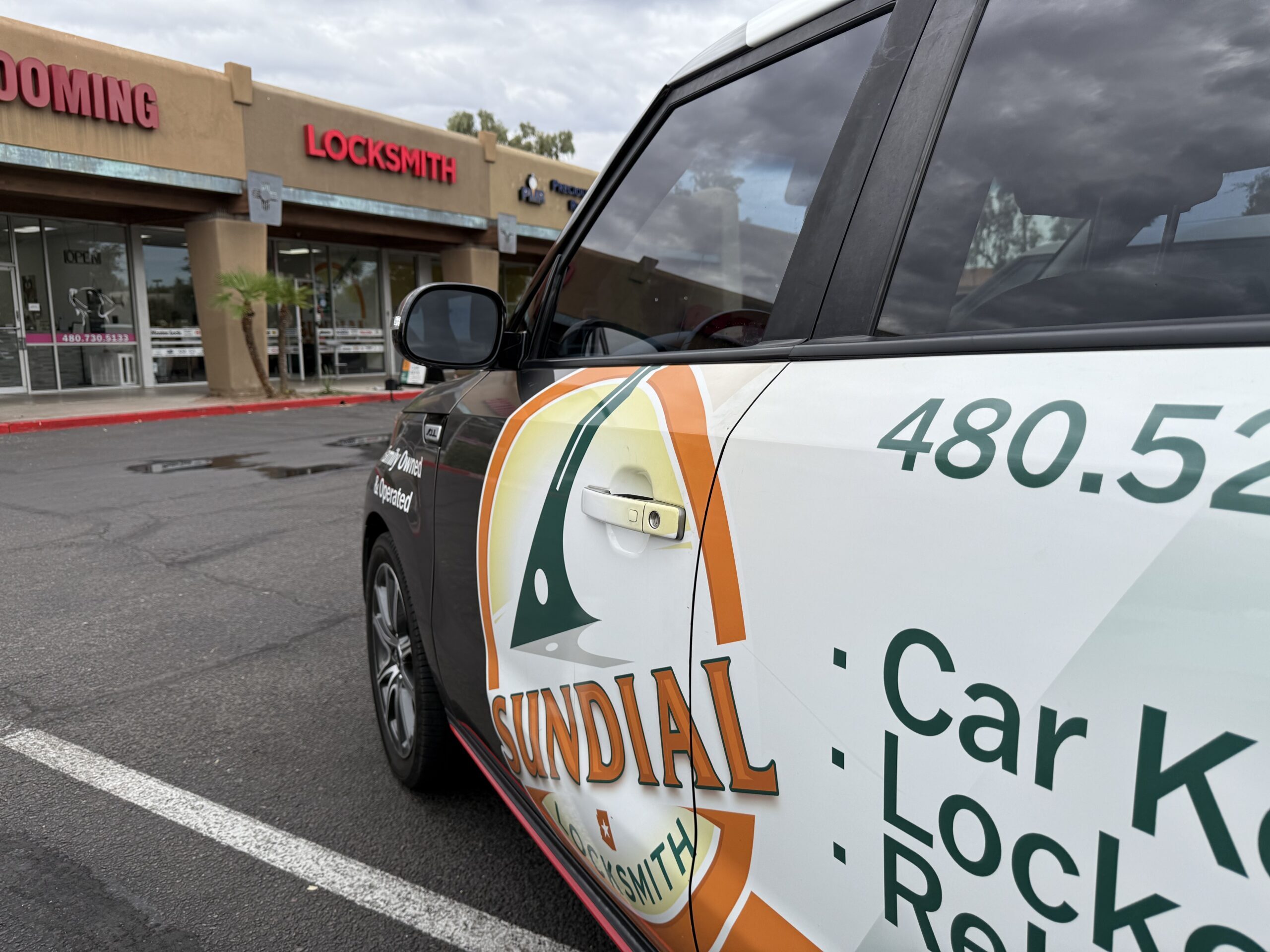 Sundial Locksmith service vehicle parked outside a strip mall with a storefront locksmith sign in the background.