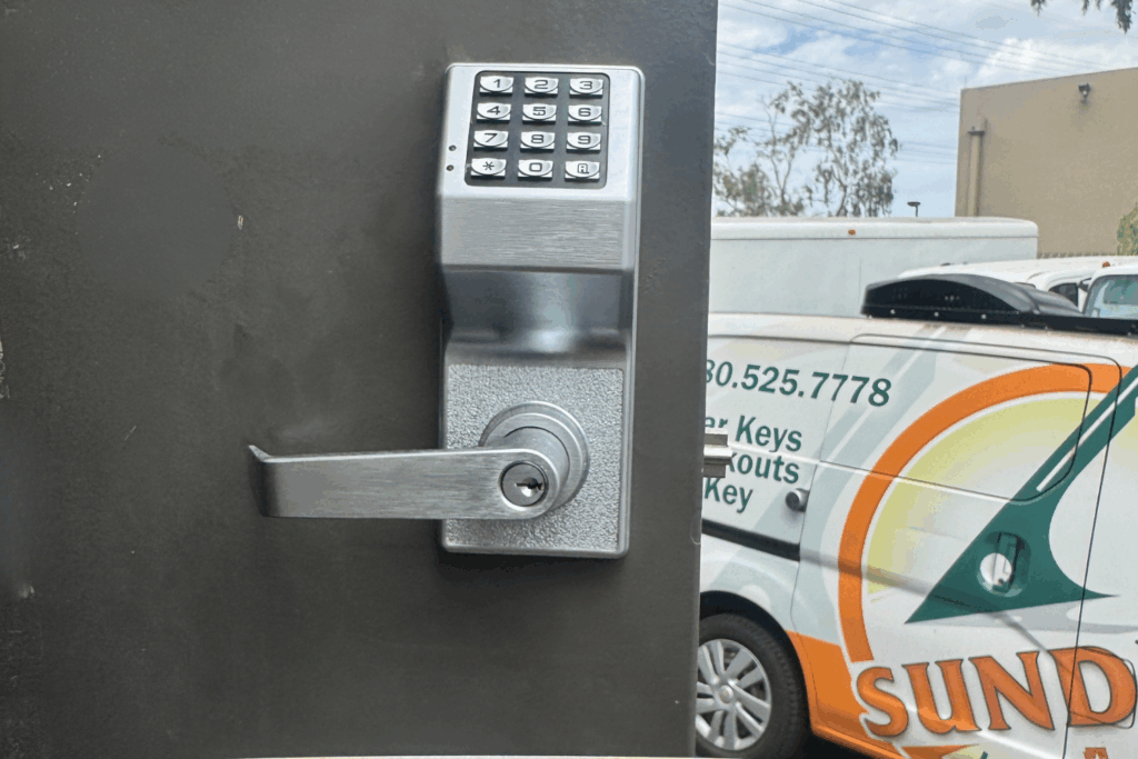 Installed commercial keypad door lock with lever handle, with a Sundial Locksmith service van in the background.