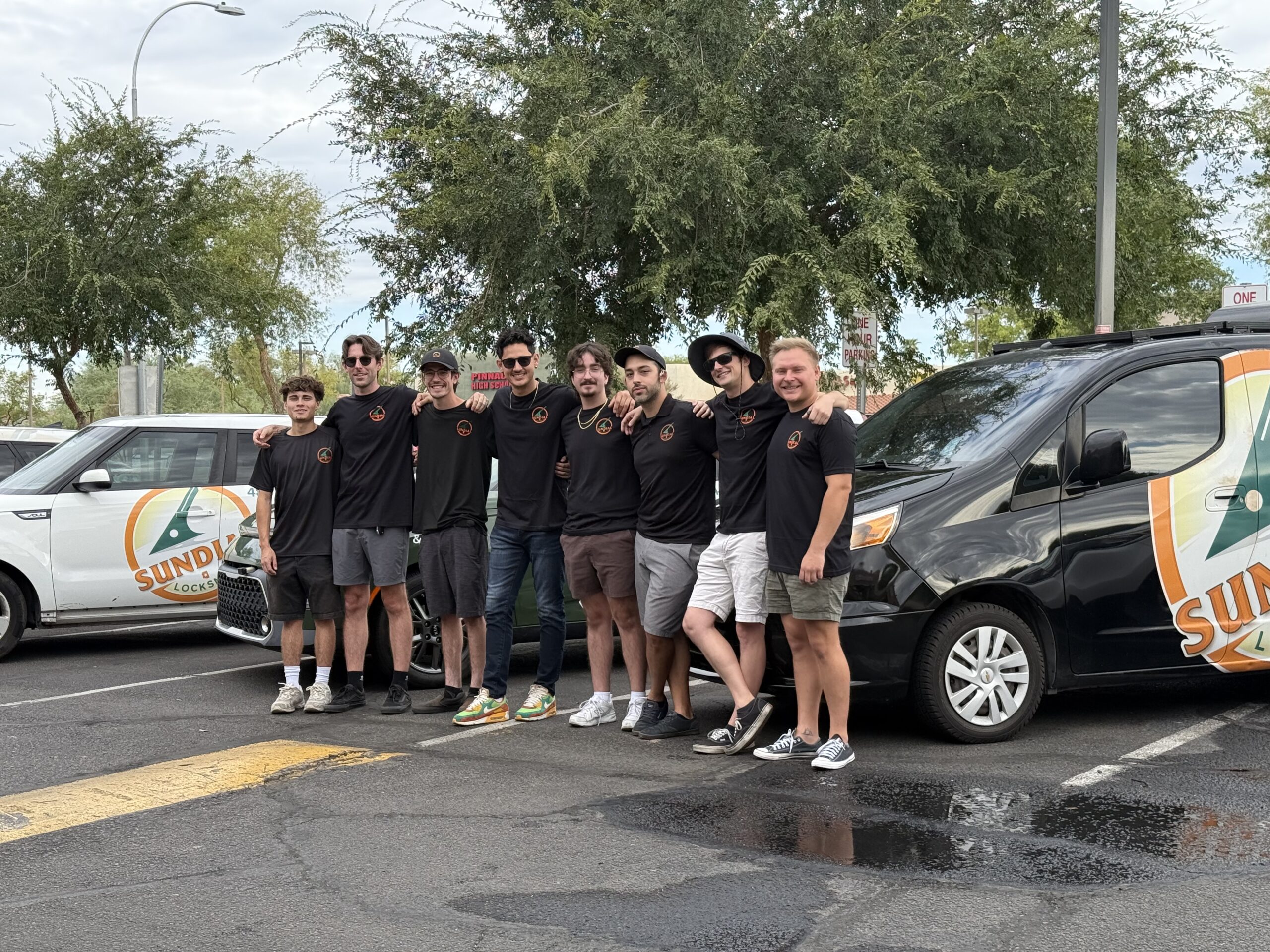 Sundial Locksmith team standing together in front of branded service vehicles in a parking lot, wearing matching uniforms.