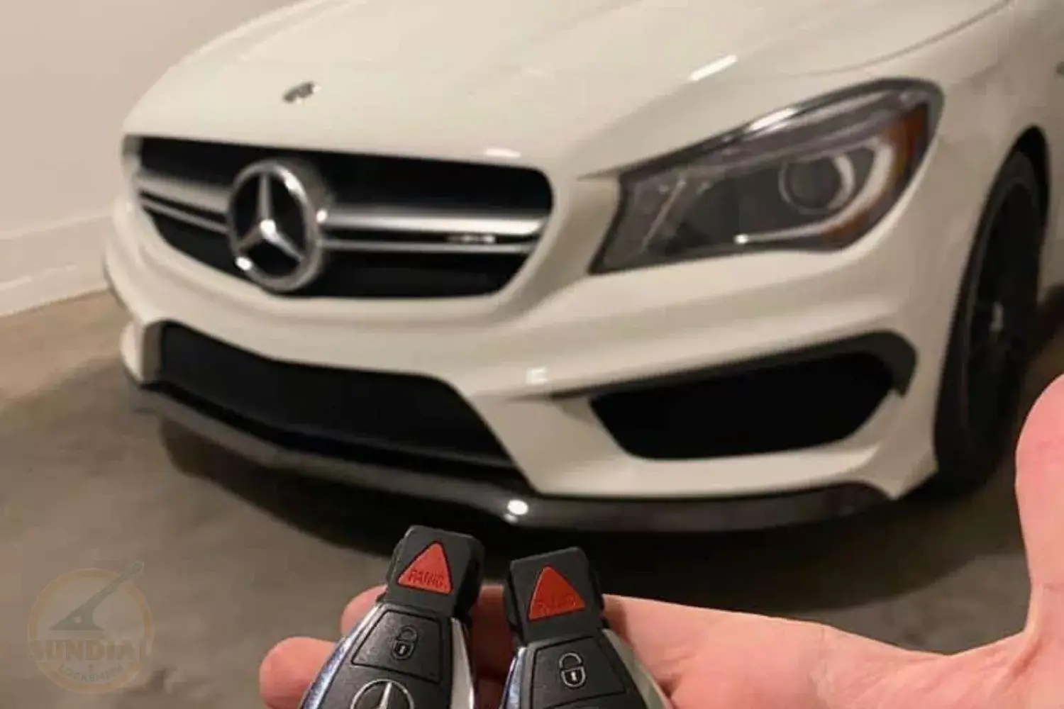 Mercedes car keys with vehicle in background.
